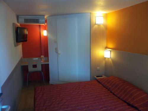 a bedroom with a bed and a door with a desk at Premiere Classe Lyon Est Aeroport Saint Exupery in Saint-Laurent-de-Mure