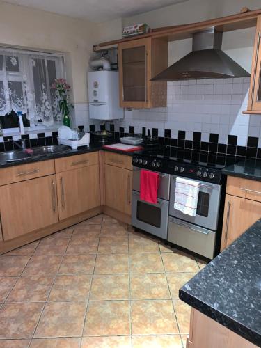 a kitchen with wooden cabinets and a stove top oven at Private Rooms with Shared Bathroom Bus Stop 8 Mins Away in Earley