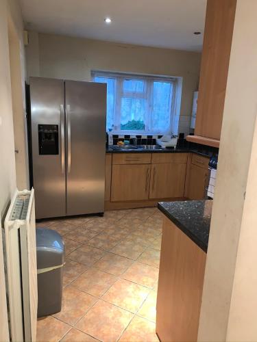 a kitchen with a stainless steel refrigerator and a window at Private Rooms with Shared Bathroom Bus Stop 8 Mins Away in Earley