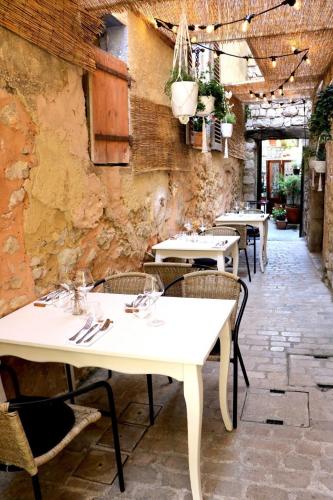 un restaurant avec des tables et des chaises blanches dans une salle dans l'établissement Maisonnette rénovée entre mer et montagne avec 4 couchages au cœur du village médiéval de Tourrettes sur loup proche st Paul de vence Grasse Gourdon Nice Cannes, à Tourrettes-sur-Loup