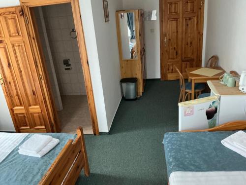 a room with two beds and a table and a bathroom at Pension Abbazia in Františkovy Lázně