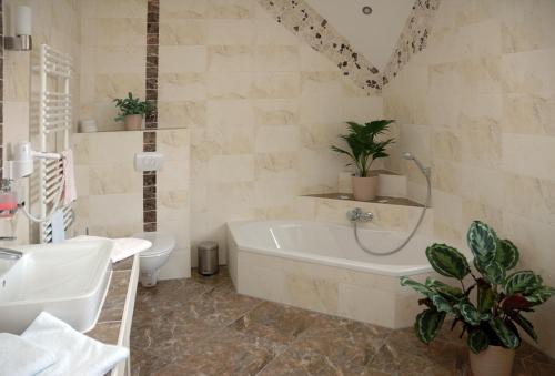 ein Badezimmer mit Badewanne, Toilette und Waschbecken in der Unterkunft Hotel Zur Wildtränke in Spremberg