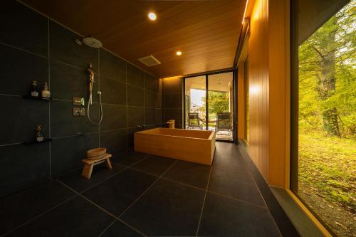 a bathroom with a tub and a shower with a window at Hakuba Jolie Maison by Jade Group in Hakuba
