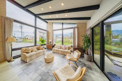 a living room with couches and chairs and large windows at Hakuba Jolie Maison by Jade Group in Hakuba