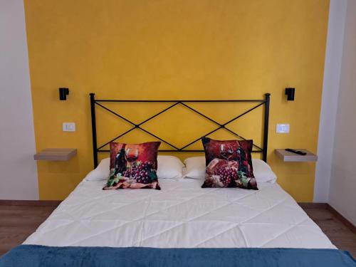 a bed with two pillows on it with a yellow wall at 8380 La Cantina di Piero&Netta in Montemerano