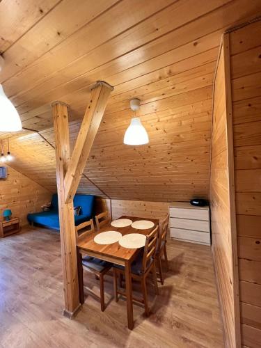 a wooden dining room with a table and chairs at Apartament nad jeziorem in Wilkasy