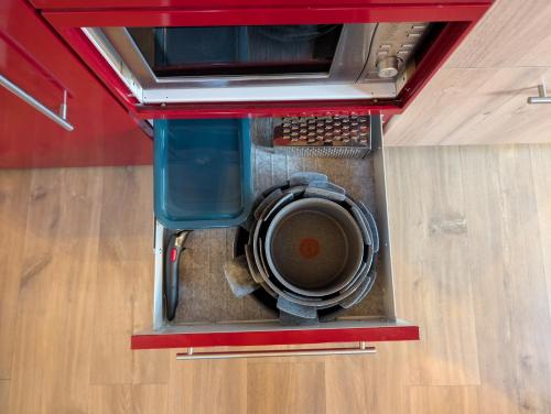 a washing machine in a red container on the floor at Le Chalet Bleu - jacuzzi in Aix-en-Provence