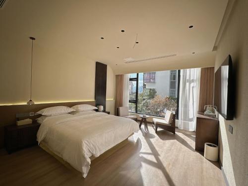 una camera da letto con un letto grande e una grande finestra di Sanqiu Designer B&B a Lijiang