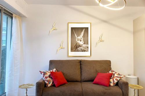 - un salon avec un canapé marron et des oreillers rouges dans l'établissement Beau studio avec accès plage, jardin, piscine, tennis, vélos, Netflix, à Cabourg