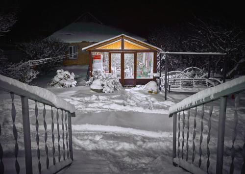 a snow covered house with a gate and a building at Family Hotel Maia - Cемейная гостиница Майя in Dashbashi