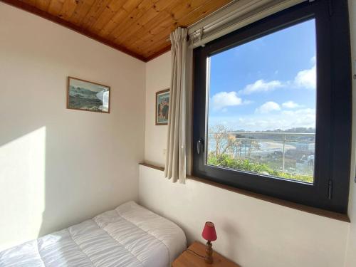 - une chambre avec une fenêtre et un lit dans l'établissement Appartement à 400m de la plage de Trestraou avec terrasse et parking - FR-1-368-329, à Perros-Guirec