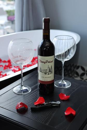 a bottle of wine and two glasses on a table at TTR Skypool View Hotel in Da Lat