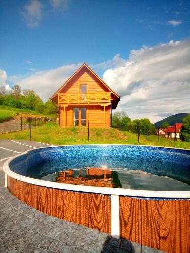 a swimming pool in front of a house at Słoneczna Chata dom Kasina Wielka in Kasina Wielka