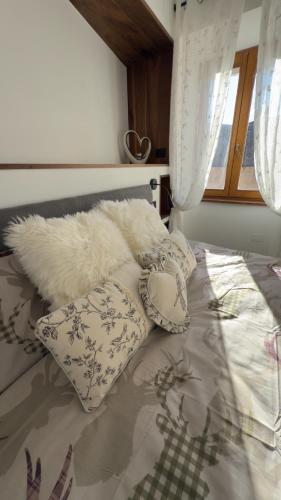 a bedroom with a bed with pillows and a window at Appartamento Alpino Cles in Cles