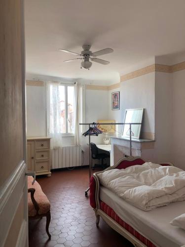 een slaapkamer met een bed, een bureau en een plafondventilator bij Proximité Palais des Festivals in Cannes