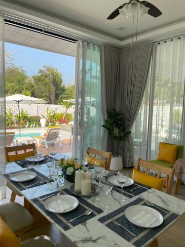 a dining room with a table and chairs and a pool at Celine Pool Villa Cha-Am in Cha Am