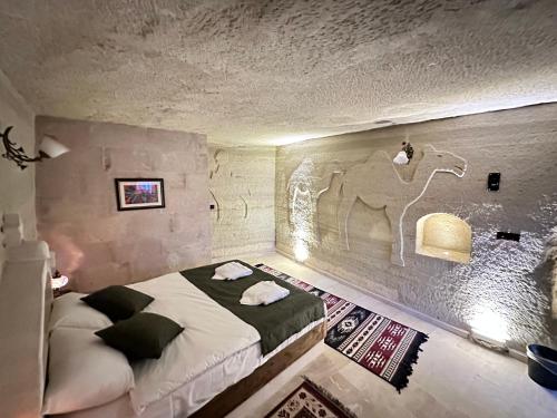 a bedroom with a bed with a camel on the wall at Turan Cappadocia Cave in Goreme