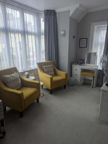 a living room with two chairs and a desk and windows at The Epperstone in Llandudno