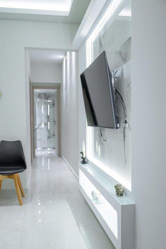 a living room with a tv on a white wall at George luxury stone apartment in Vonitsa