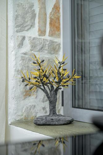 a small tree sitting on a table next to a window at George luxury stone apartment in Vonitsa