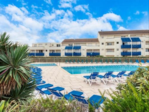 une piscine avec des chaises longues et un bâtiment dans l'établissement Logement au bord de l'océan avec piscine, à Lacanau-Océan