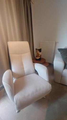 a living room with a white chair and a couch at Maison de la mer in Blankenberge