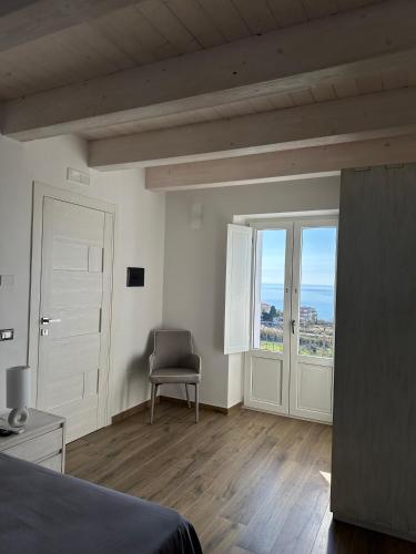 a bedroom with a bed and a chair and a window at La Casetta della Nonna in Belmonte Calabro