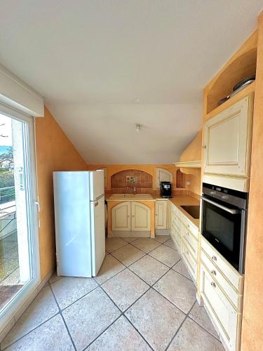 une cuisine avec un réfrigérateur blanc et une fenêtre dans l'établissement Appartement vue sur le Chateau, à Vétraz-Monthoux