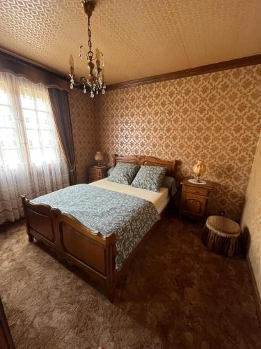 une chambre avec un grand lit et un lustre dans l'établissement Spacieuse maison de village, à Luché-Pringé