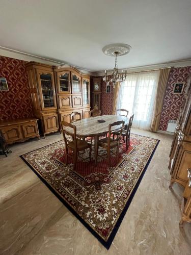 une salle à manger avec une table et des chaises sur un tapis dans l'établissement Spacieuse maison de village, à Luché-Pringé