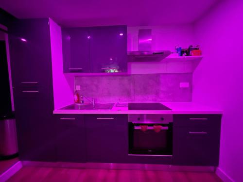 une cuisine avec éclairage rose dans l'établissement Nuit magique jacuzzi, terrasse & lit motorisé - 008, à Rouen