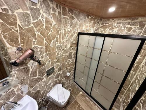 a stone bathroom with a toilet and a mirror at Turan Cappadocia Cave in Goreme