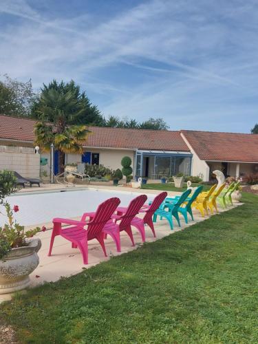 a row of colorful chairs sitting next to a pool at La Galerne in Neuville-de-Poitou