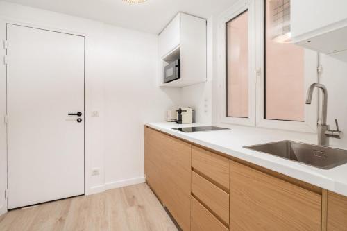 - une cuisine avec des placards blancs, un évier et une porte dans l'établissement SERENERS - Charming Serviced Apartments - Saint Germain, à Paris