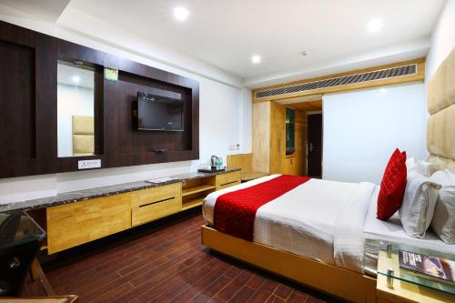 a bedroom with a bed and a flat screen tv at Airport Hotel Grand in New Delhi