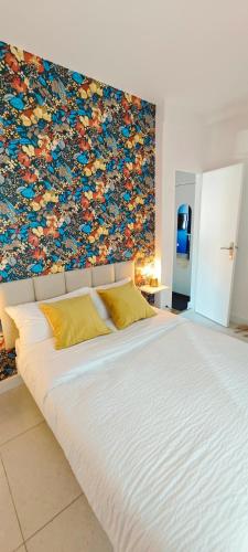 - un grand lit blanc dans une chambre dotée d'un mur coloré dans l'établissement Appartement T2 cœur de Dinan, à Dinan