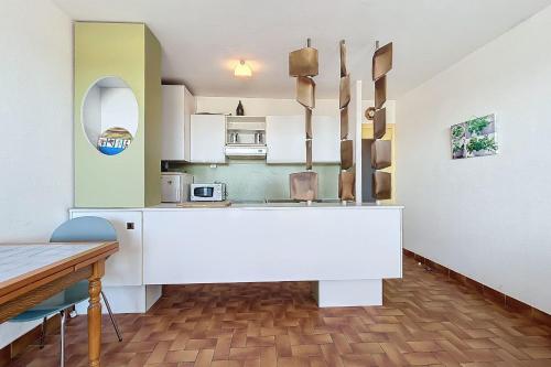 une cuisine avec un comptoir blanc et une table dans l'établissement Charming T2 with terrace on the seafront, à Port-la-Nouvelle