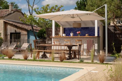 a patio with a table and an umbrella next to a pool at Le Mas Gascon - Maison de vacances 4 étoiles avec piscine et vue proche de Lectoure in Marsolan