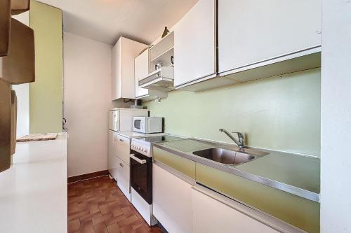 une cuisine avec des armoires blanches et un évier dans l'établissement Charming T2 with terrace on the seafront, à Port-la-Nouvelle