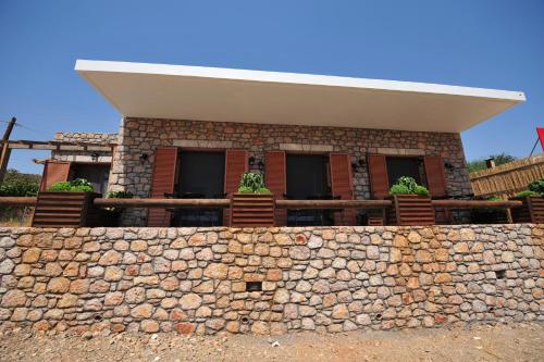 a building behind a stone wall with potted plants at Casa Gustosa Μονεμβασιά in Monemvasia
