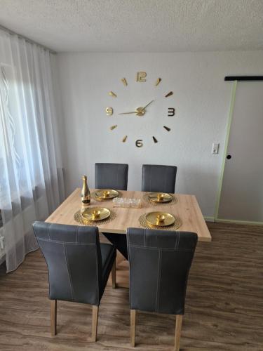 a dining room table with chairs and a clock on the wall at Filder Apartment in Ostfildern