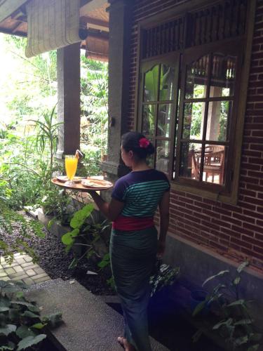 una donna che tiene un tavolo con un drink sopra di Bali Asli Lodge by EPS ad Ubud
