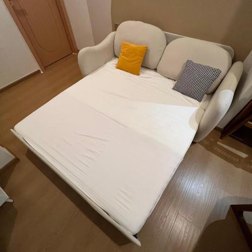 a white couch with a yellow pillow on it at Casabella Homestay 201 Batam Penuin in Nagoya