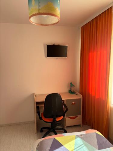 a bedroom with a chair and a desk and a television at Apartament SUN Drăgășani in Drăgăşani