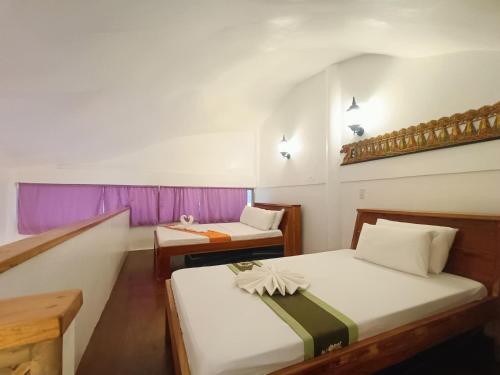 two beds in a room with purple curtains at Casa de Arte in Boracay