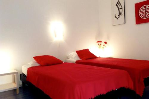 - 2 lits dans une chambre avec des draps rouges dans l'établissement Dans la cours du château by Miss K, à Chaintré