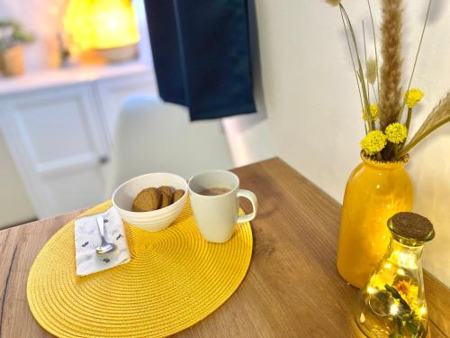 a table with two cups of coffee and a vase at Oázis Apartmanház Balatonalmádi in Balatonalmádi