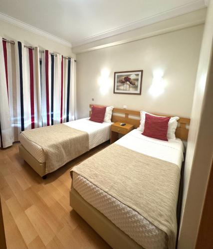 a hotel room with two beds and curtains at Paradouro in Lisbon