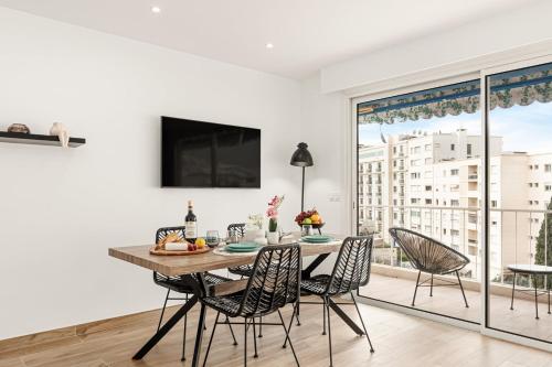 une salle à manger avec une table et des chaises et une grande fenêtre dans l'établissement Suite Sérénade - Appartement à Cannes, à Cannes