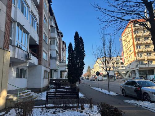 a city street with benches and buildings in the snow at Apartament SUN Drăgășani in Drăgăşani